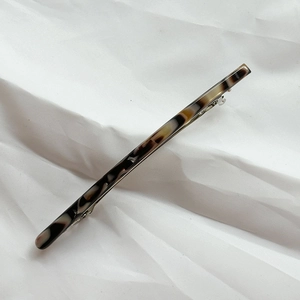 Detail view of large acetate spring clip showing dark tortoiseshell pattern texture