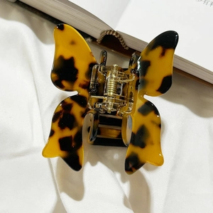 Top macro view of a vintage tortoiseshell butterfly hair claw clip on white fabric