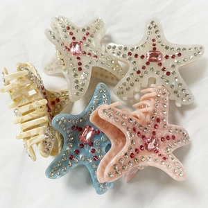 Pinze per capelli a stella marina con strass scintillanti in colori assortiti su tessuto bianco