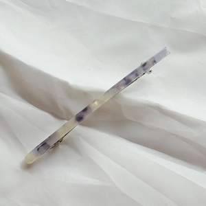 Detailed macro view of the marble patterned acetate hair clip with silver spring metal back