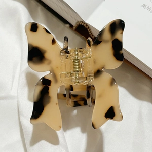 Detailed close-up of butterfly hair claw clip with tortoise shell pattern on fabric background