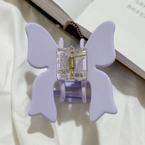 Close-up of lavender butterfly hair claw clip featuring matte texture and golden spring