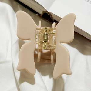 Detailed top view of a beige matte butterfly hair claw clip with golden metal spring