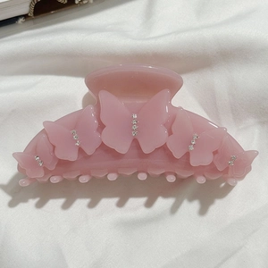 Vue détaillée d'une pince à cheveux rose en acétate avec papillons strassés sur tissu
