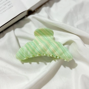 Detailed shot of mint green marble acetate hair claw clip on white fabric background
