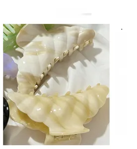 Macro shot of cream acetate hair claw clip with marble texture on white silk fabric