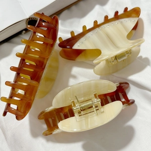 Three acetate shark hair clips with marble patterns and rhinestones on white fabric