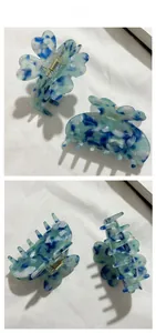 Vue détaillée de pinces à cheveux papillon marbrées bleu et blanc sur fond de tissu blanc