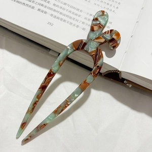 Forcina a U in acetato verde marmorizzato su un libro aperto per uno stile vintage