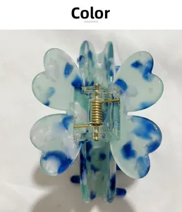 Détail d'une pince à cheveux trèfle en acétate avec texture marbrée bleue et verte
