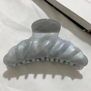 Macro shot of large pearlescent grey hair claw clip with a detailed wavy texture surface