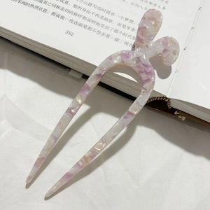 Dettaglio di una forcina per capelli in acetato marmorizzato viola su un libro