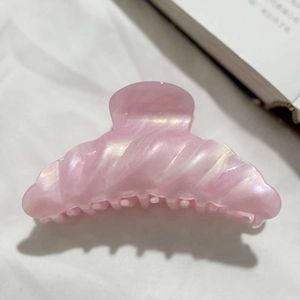 Macro shot of pink pearlescent hair claw clip with shell texture on white fabric