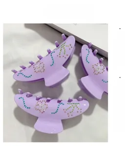 Große lilafarbene Haarspangen aus Acetat mit Strass-Blumenmuster in der Nahaufnahme
