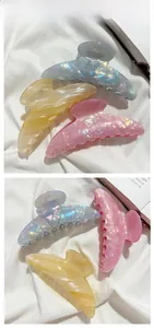 Iridescent pearlescent claw clips in pink, blue, and yellow with shell texture details