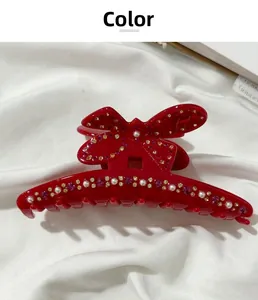Dettaglio del fermaglio a farfalla rosso scuro con perle e cristalli scintillanti