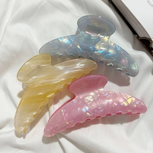 Three elegant French large hair claws in blue, amber, and pink on white fabric background