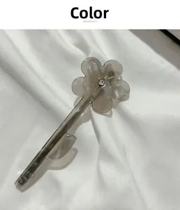 Détail de la pince à cheveux fleur en acrylique gris fumé avec un strass étincelant
