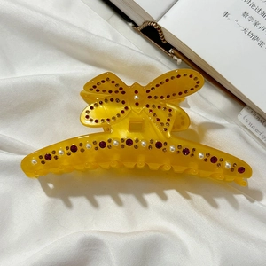 Dettaglio del fermaglio a farfalla giallo con strass viola e perle finte eleganti