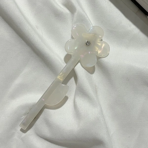Détail d'une pince à cheveux fleurie nacrée avec cristal et finition dorée élégante
