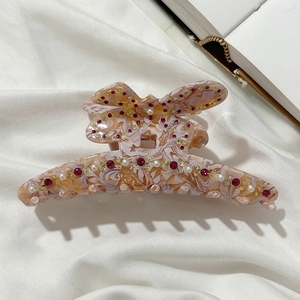 Dettaglio molletta a farfalla effetto marmo rosa con strass e decorazioni di perle