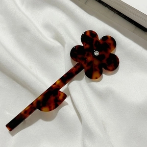 Gros plan détaillé d'une pince à cheveux fleur en écaille avec un strass blanc étincelant