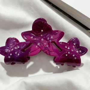 Macro view of purple gradient acetate flower hair claw clip with sparkling rhinestones