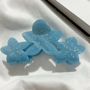Detail of light blue floral acetate hair claw clip with rhinestones and pearlescent finish