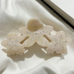 Detail view of acetate flower hair claw clip with rhinestones and marble texture