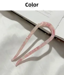 Detail of pink marble acetate U-shaped hair pin for bun hairstyles on white fabric