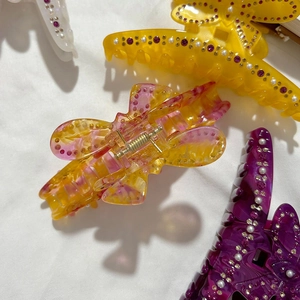 Set di fermagli per capelli a farfalla con strass e perle su sfondo di tessuto bianco