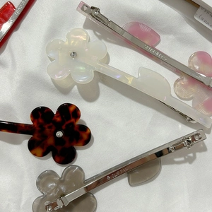 Barrettes à fleurs en acétate avec centre en cristal sur fond de tissu blanc épuré