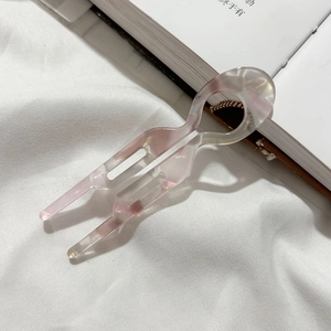 Épingle à cheveux en U en résine marbrée rose et blanc sur fond de tissu blanc