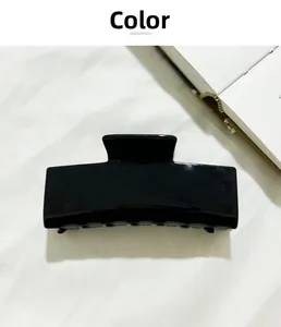 Vue détaillée de la pince à cheveux rectangulaire noire brillante sur tissu blanc