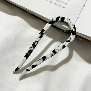 Detail showing U-shaped acetate hair pin with marble pattern on a white fabric background