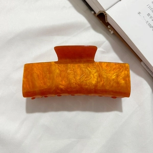 Détail d'une pince à cheveux en acrylique ambré marbré avec un ressort métallique robuste