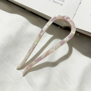 Detail of minimalist U-shaped acetate hair pin with purple marble texture on fabric