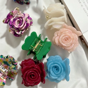 Elegante französische Rosen-Haarklammern in verschiedenen Farben auf weißem Stoffgrund