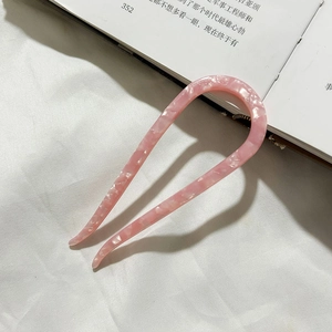 Close-up of pink marble texture acetate hair pin on white fabric and book
