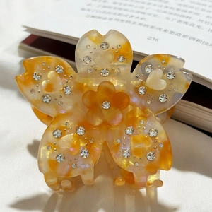 Détail d'une pince à cheveux fleur en acétate ambré avec strass et charms en cœur