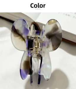 Detailed top view of butterfly hair claw clip with purple tortoiseshell pattern on a book