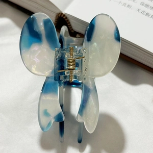 Close-up of butterfly hair claw with blue and white marble pattern and pearl glitter details