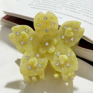 Détail de la pince à cheveux fleur en acétate jaune clair avec strass et relief en cœur
