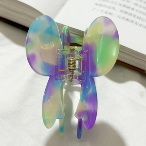 Macro view of butterfly hair claw clip with colorful iridescent swirl pattern and metal spring