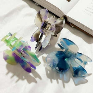 Three elegant acetate butterfly hair claws with marble texture on white fabric