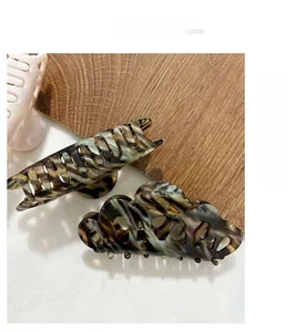 Vue détaillée des pinces à cheveux en acétate avec motif écaille vert et ambre
