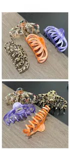 Detail view of large acetate claw clips in tortoiseshell, purple, orange, and marble patterns