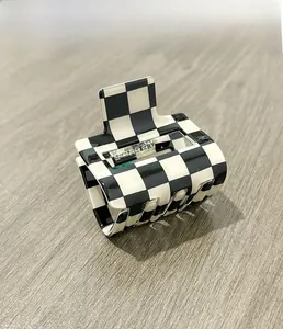 Detail view of the black and white checkerboard hair claw clip on a light wooden table