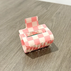 Macro view of pink and white checkered hair claw clip with glossy finish and strong teeth