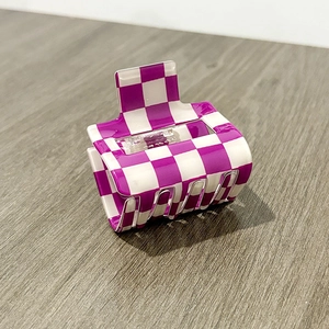 Detail view of the purple and white checkered PVC hair claw clip on a wooden surface